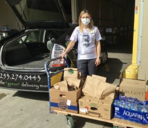 Woman in Seahawks jersey with cart full of food donations